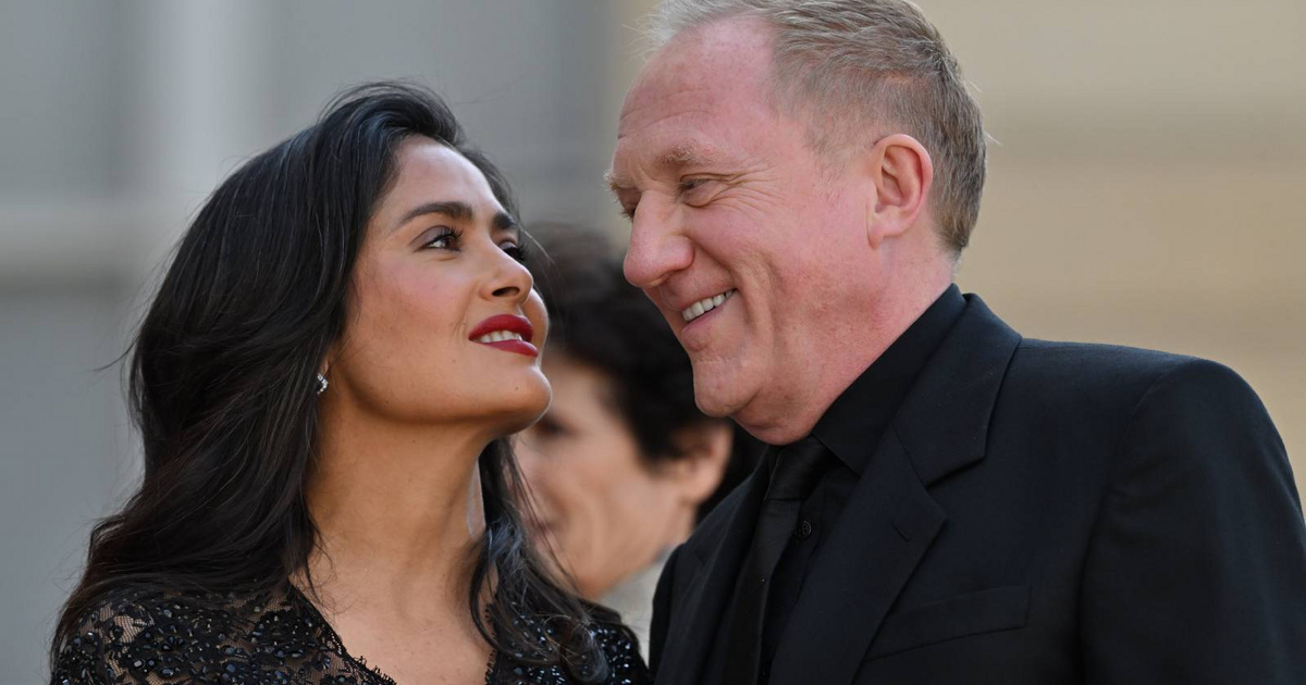 A Salma Hayek elegánsan ragyog vörös szőnyegen: áttetsző csipkefelsőben férjével ölelkezik